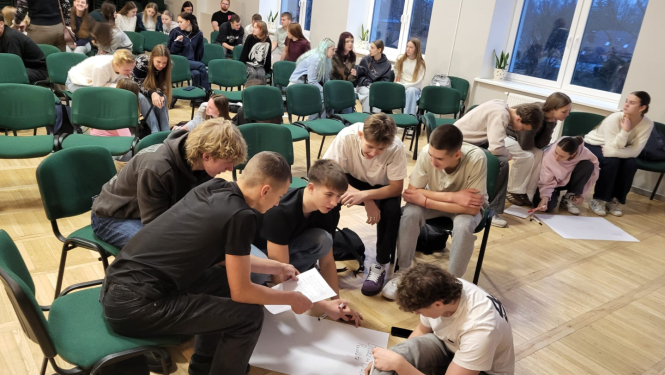 Jaunieši piedalās interaktīvā darbnīcā, diskutē un strādā pie uzdevumiem auditorijā.