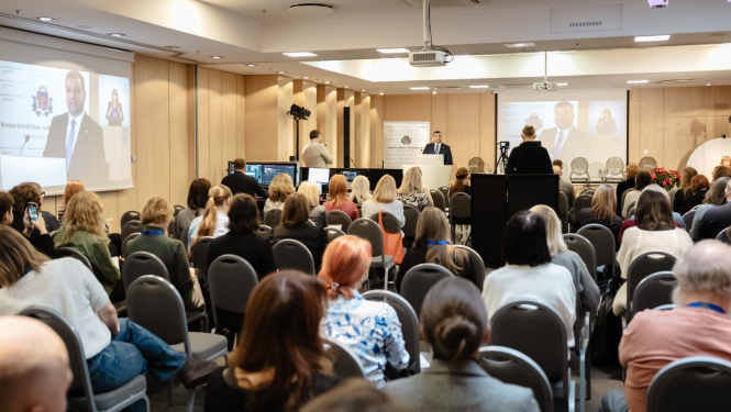 Konferences “Brīvprātīgais darbs Latvijā — vakar, šodien un rīt” foto ar plašu auditoriju, skatuvi un runātāju.