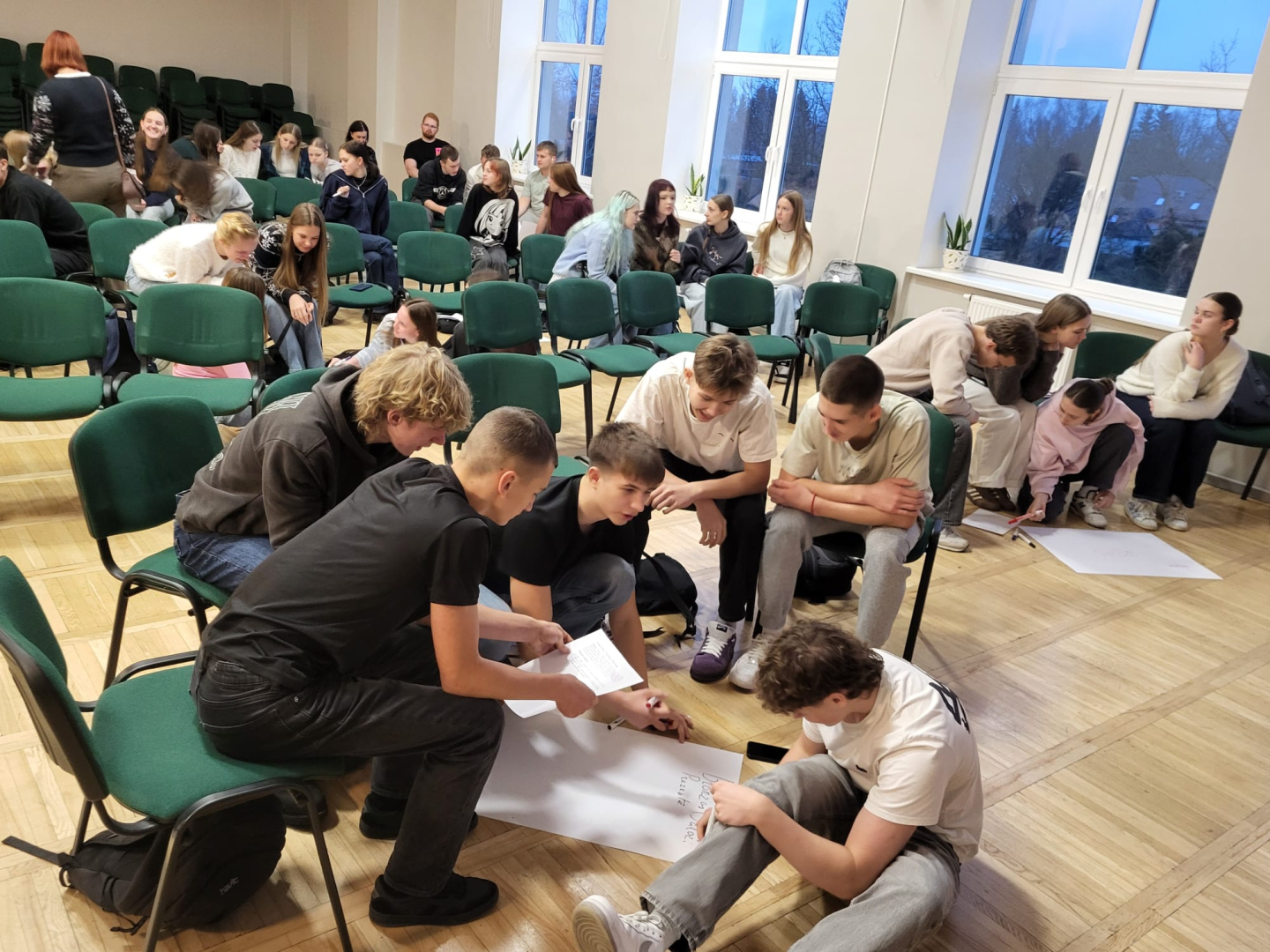 Jaunieši piedalās interaktīvā darbnīcā, diskutē un strādā pie uzdevumiem auditorijā.