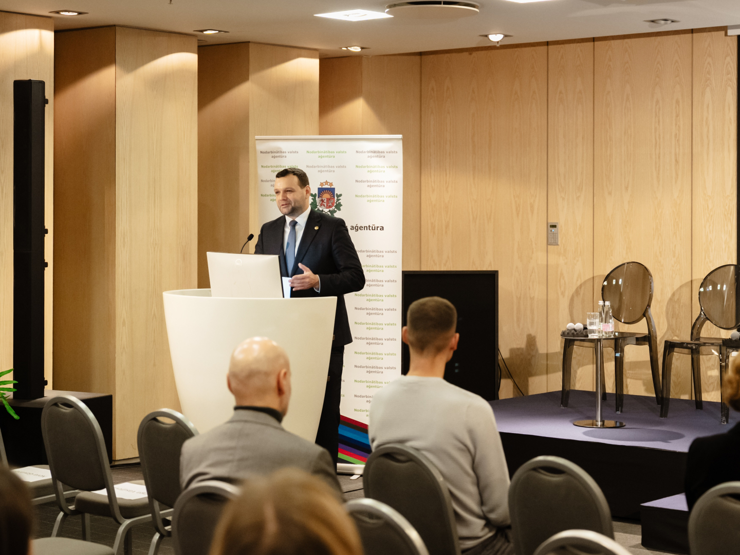 Konferences “Brīvprātīgais darbs Latvijā — vakar, šodien un rīt” foto ar plašu auditoriju, skatuvi un runātāju.