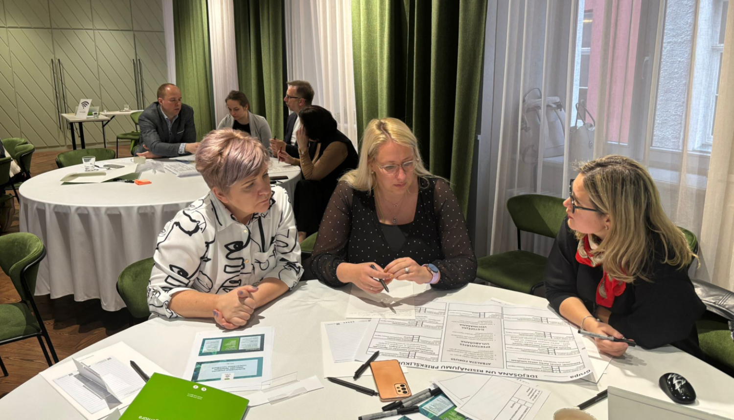 Pie galda sēž četras domnīcas dalībnieces, kas aktīvi diskutē.